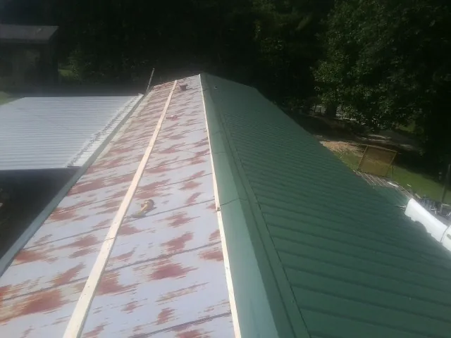 Old rusted panels beside newly installed green metal roofing — Wind Damage Roof Repair by Roofing Brothers in Wadmalaw Island