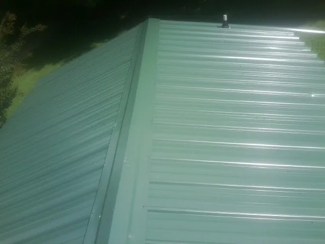 New green metal panels meeting at the ridge of a roof — Flat Roof Repair work by our crew in Wadmalaw Island