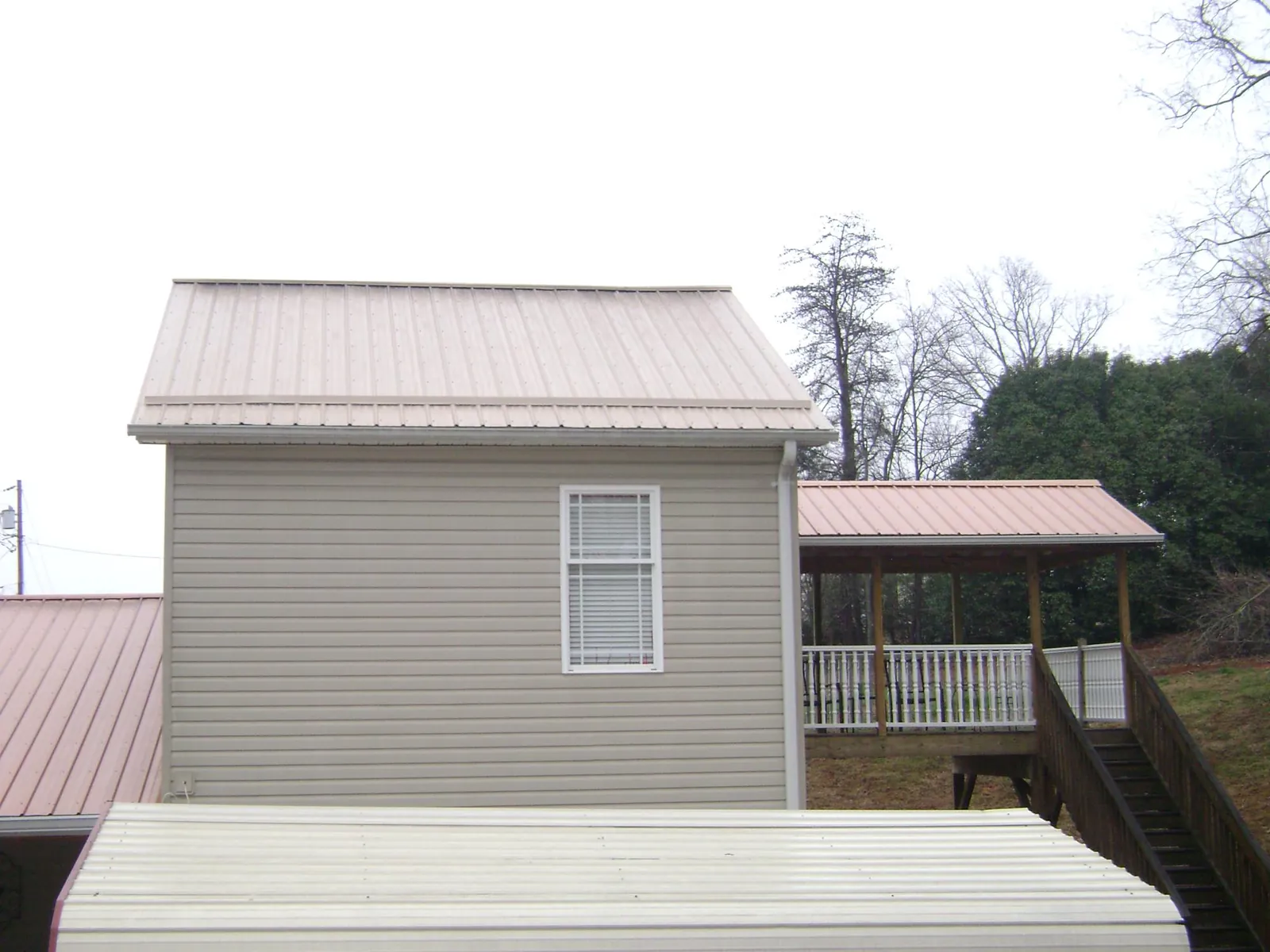 Tan metal roofs on a two story addition and attached porch, from a Roof Replacement job in Wadmalaw Island