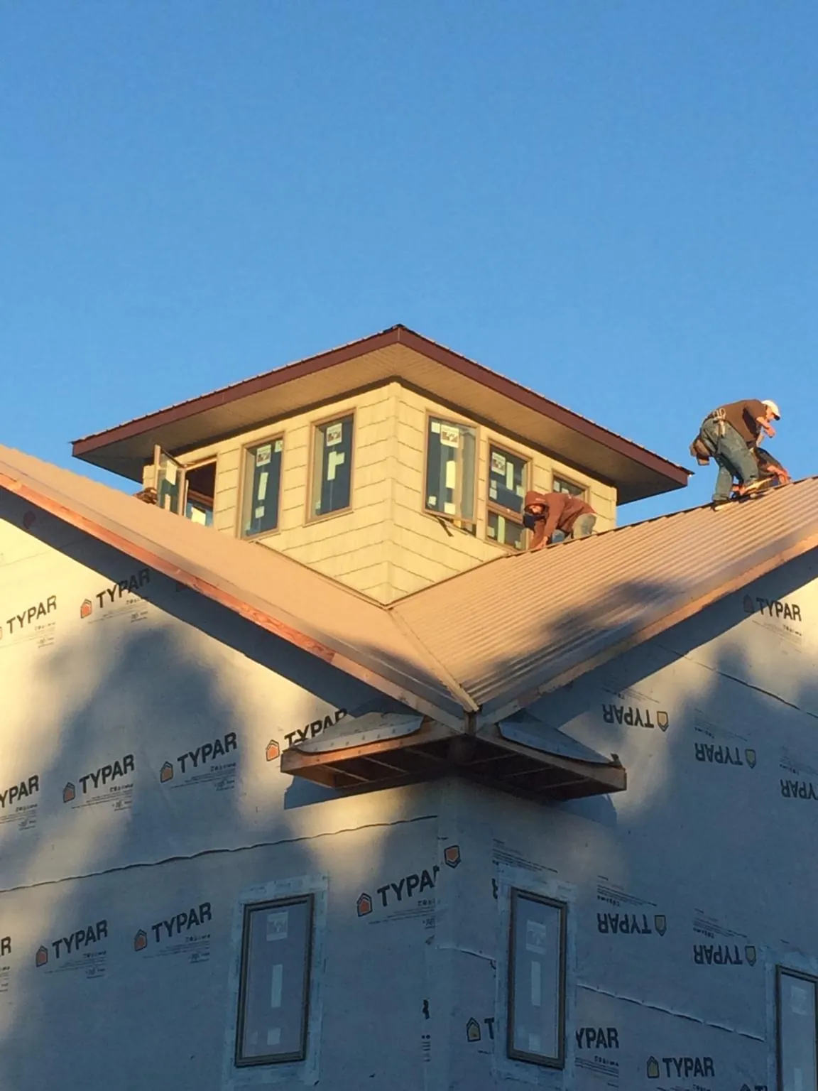 Roofers working around a rooftop cupola on a new metal roof at sunset — Roof Waterproofing in Wadmalaw Island by Roofing Brothers